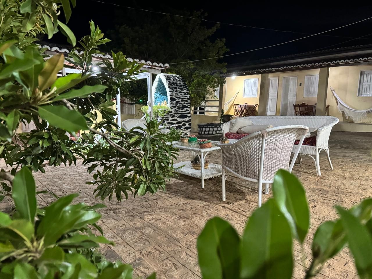 Pátio do Recanto da Flor à noite, com as casas, redes e cadeiras
